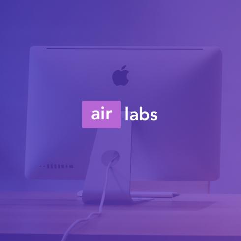 Monitor iMac z logiem Apple i nakładką graficzną 'air labs' na fioletowym tle.