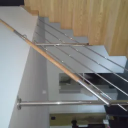 Nowoczesne schody drewniane z metalowymi balustradami i drewnianą poręczą, widok z góry, minimalistyczny design.