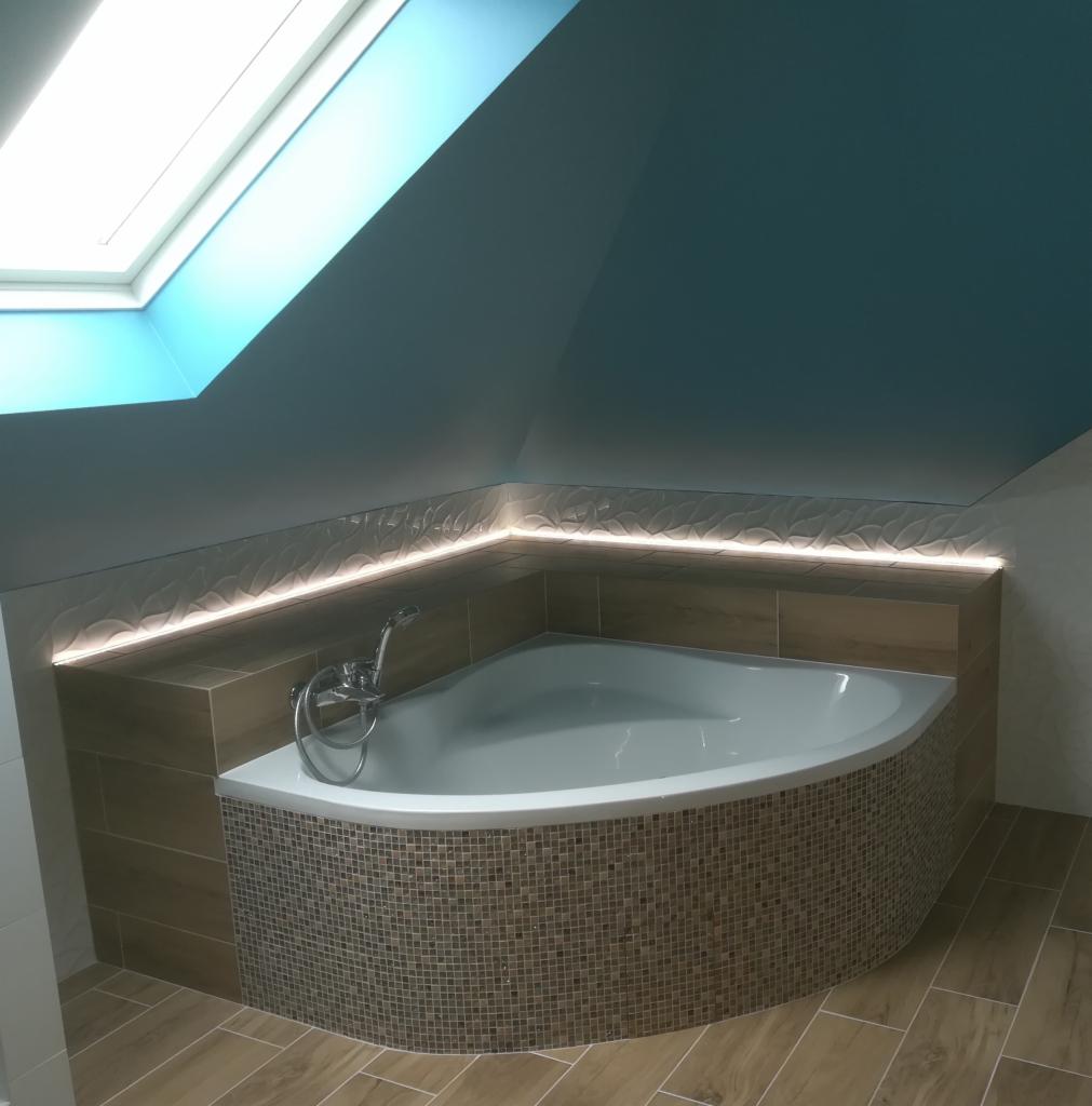 Narożna wanna obudowana mozaiką w łazience na poddaszu z oknem dachowym i podświetleniem LED wzdłuż ściany