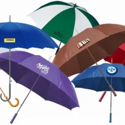 Zestaw rozłożonych parasoli w różnych kolorach z nadrukowanymi logotypami firm: Kropka Beskidu, Milka, PZU, Coca-Cola, Bond, 3Bit, Stabra.