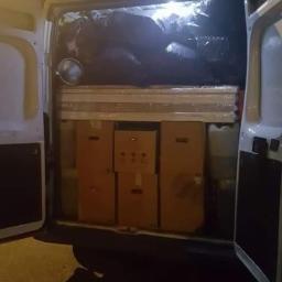 Zdzisław Bolen Dar-Trans - Wnętrze białego furgonetki załadowane kartonami, meblami owiniętymi folią i workami, widoczne przy otwartych tylnych drzwiach w słabym oświetleniu.