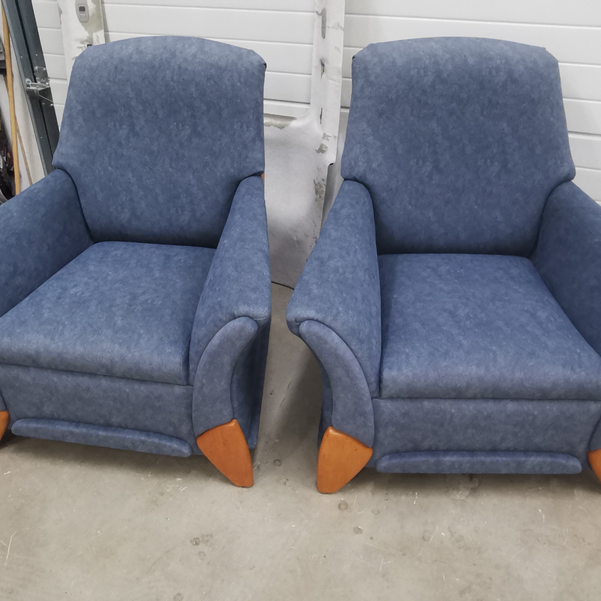 Dwa identyczne, odnowione fotele z niebieską tapicerką i drewnianymi nóżkami, ustawione obok siebie w jasnym pomieszczeniu.