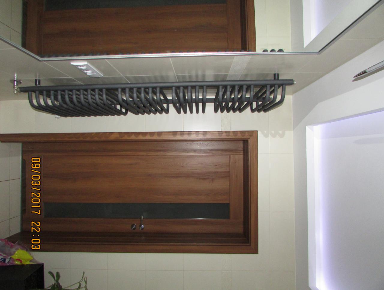 Łazienka z drewnianą szafką pod umywalką, grzejnikiem drabinkowym w kolorze grafitowym pod sufitem i oświetleniem LED w niszy ściennej.