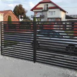 Nowoczesna brama wjazdowa z poziomych profili w kolorze antracytowym, z automatyką i kamiennymi słupkami, widok na posesję z zaparkowanym samochodem.