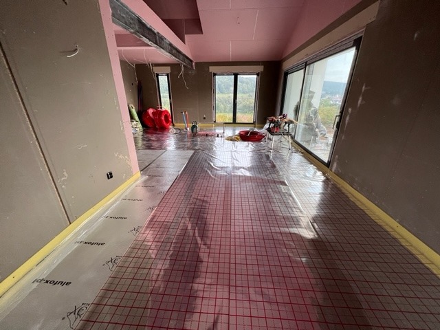 Montaż folii grzewczej z siatką w pomieszczeniu z dużymi oknami w miejscowości Dobra, widoczne przygotowania do instalacji ogrzewania podłogowego.