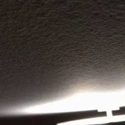 Szary sufit z widoczną fakturą i linią światła LED wzdłuż krawędzi.