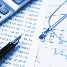 Kalkulator, długopis i okulary na arkuszu z danymi finansowymi i wykresem, chłodna tonacja.