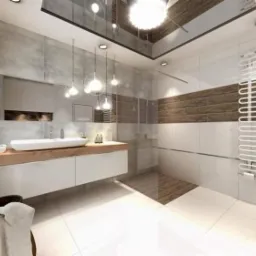 Nowoczesna łazienka z podwieszaną umywalką na drewnianym blacie, lustrem, dekoracyjnym oświetleniem sufitowym i grzejnikiem drabinkowym na białej ścianie z poziomym pasem brązowych płytek.