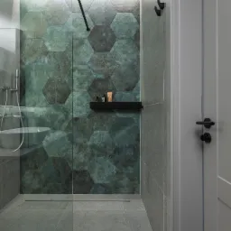 Nowoczesna łazienka z kabiną prysznicową typu walk-in, wyłożoną heksagonalnymi płytkami w odcieniach zieleni i szarości, z czarną półką na kosmetyki i deszczownicą.