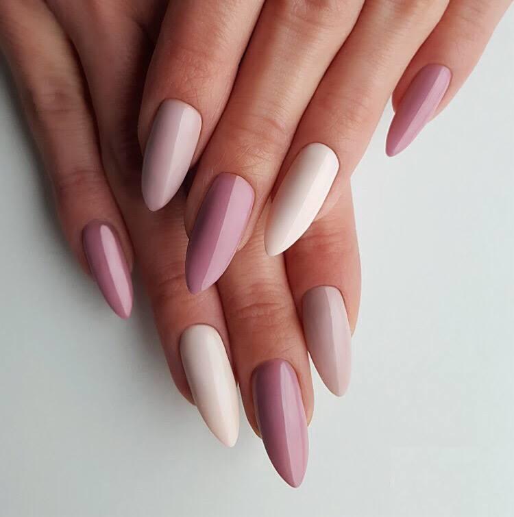 Dłoń z pomalowanymi paznokciami w odcieniach różu i beżu, migdałowy kształt, gładka powierzchnia, zbliżenie na dłoń na jasnym tle.