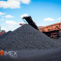 Góra czarnego węgla na placu składowym, z widocznymi elementami maszyn do sortowania i transportu w tle oraz logo firmy POLOIMEX w dolnej części kadru.