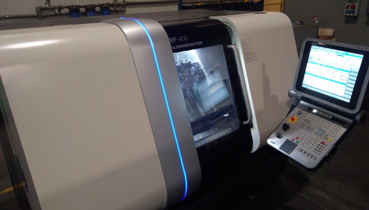 Nowoczesna frezarka CNC DMG Gildemeister EF 400 z panelem sterowania, widoczne wnętrze komory roboczej z obrabianym elementem.