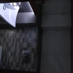 Nowoczesna łazienka w odcieniach szarości z podświetleniem LED, widok z góry na umywalkę, toaletę i płytki na ścianach.