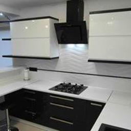 Meble na wymiar - Nowoczesna kuchnia z białymi górnymi szafkami z czarnymi obramowaniami i czarnymi dolnymi szafkami z białym blatem, czarny okap nad płytą gazową.