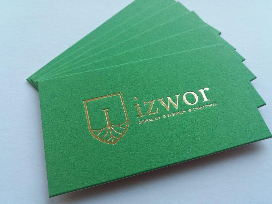 Stos zielonych wizytówek z wytłoczonym złotym logo i tekstem 'izwor Genealogy Research Data Mining' na teksturowanym papierze.