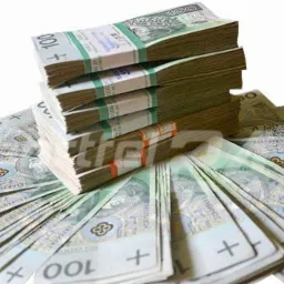 Stos zapakowanych banknotów 100 PLN, ułożonych na rozłożonych pojedynczych banknotach tego samego nominału, na białym tle.