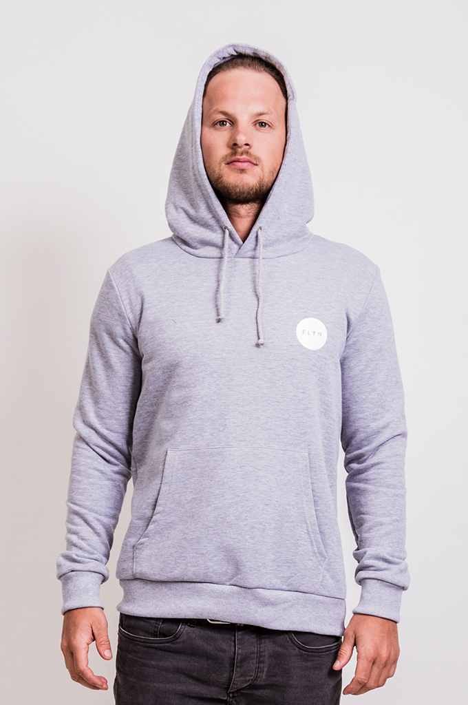 Mężczyzna prezentuje szarą bluzę z kapturem i logo FLYTR na piersi, na jasnym tle.