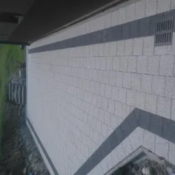 Nowoczesny taras wyłożony jasnoszarą kostką z ciemnoszarymi pasami, widoczna studzienka odpływowa, w tle trawnik i schody.