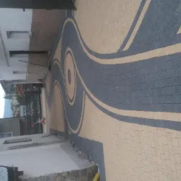 Ułożona kostka brukowa w kolorach szarym i beżowym tworząca dekoracyjny wz&oacute;r z motywem spirali na podjeździe.