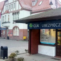 Biuro CUK Ubezpieczenia z szyldem reklamowym i flagą informującą o 30 ubezpieczycielach w jednym miejscu, widok z ulicy Strążacka.