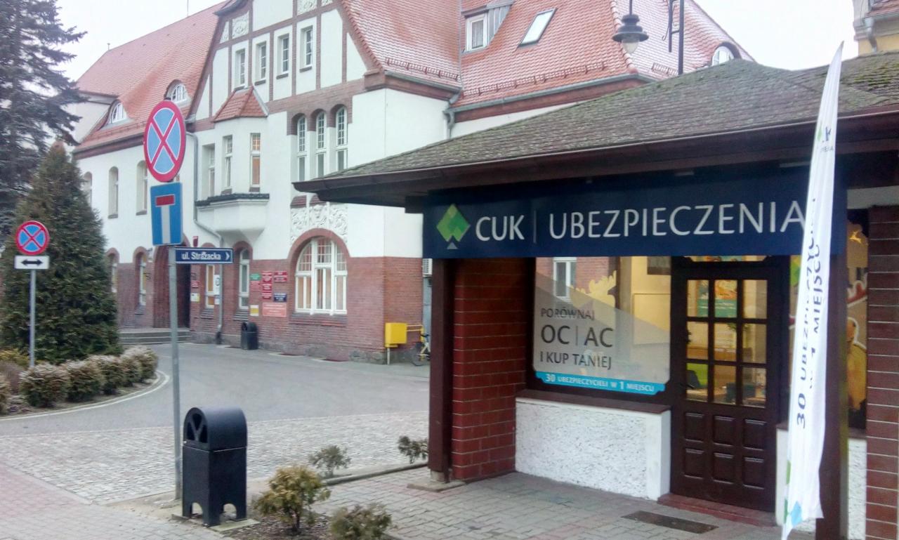 Biuro CUK Ubezpieczenia z szyldem reklamowym i flagą informującą o 30 ubezpieczycielach w jednym miejscu, widok z ulicy Strążacka.