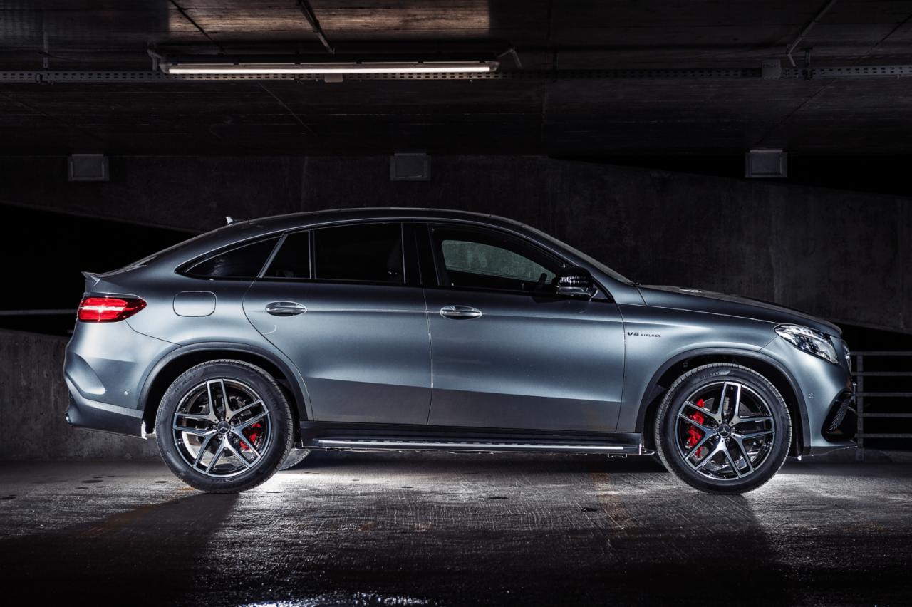 Szary samochód Mercedes-Benz GLE Coupe AMG zaparkowany w ciemnym garażu, widok z boku, z widocznymi czerwonymi zaciskami hamulcowymi i oświetleniem sufitowym.