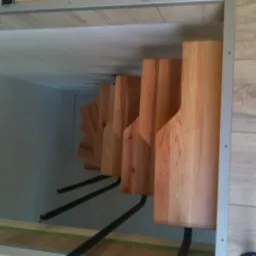 Wnętrze szafki z zamontowanymi drewnianymi półkami na buty, wykonanymi z jasnego drewna, widoczne czarne metalowe wsporniki, Alwernia.