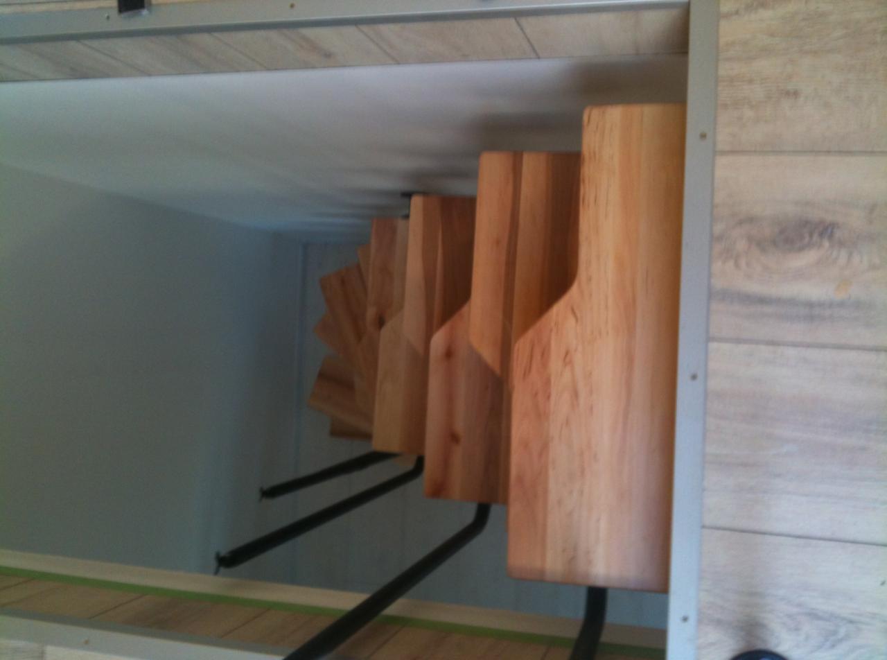 Wnętrze szafki z zamontowanymi drewnianymi półkami na buty, wykonanymi z jasnego drewna, widoczne czarne metalowe wsporniki, Alwernia.