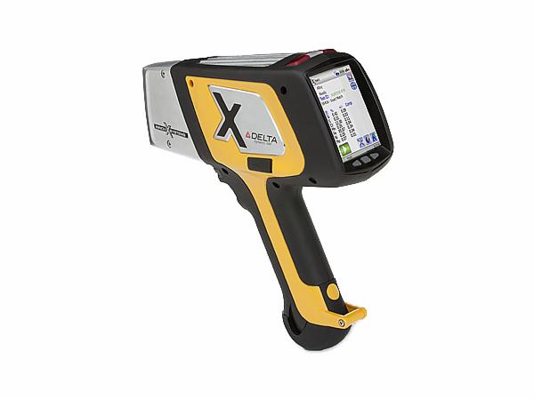 Przenośny analizator XRF Delta z wyświetlaczem pokazującym wyniki pomiarów, obudowa w kolorze srebrnym, czarnym i żółtym.
