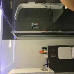 Nowoczesna łazienka z kabiną prysznicową typu walk-in, białą armaturą i podświetleniem LED wzdłuż ściany.