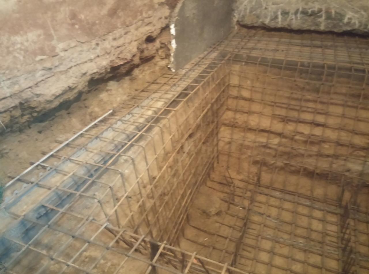 Zbrojenie fundamentów w wykopie, widok z góry. Stalowa siatka tworzy szkielet pod budowę, ziemia w tle. Detal konstrukcji.