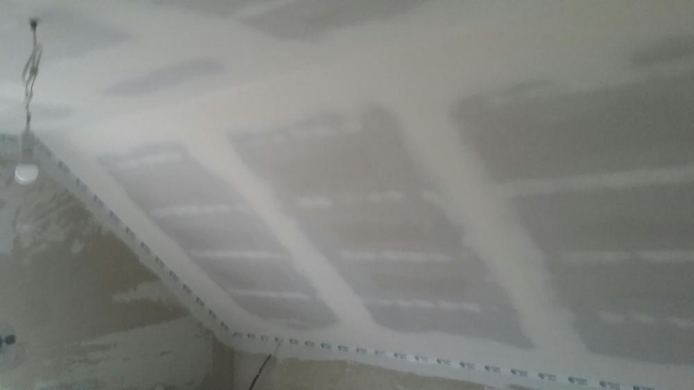 Skośny sufit poddasza z zamontowaną płytą gipsowo-kartonową, widoczne łączenia płyt przed szpachlowaniem, kabel oświetleniowy zwisający z sufitu.