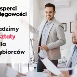 Prelegent w szarej marynarce prowadzi warsztaty dla przedsiębiorców, logo firmy w lewym górnym rogu, uczestnicy siedzą przy stole.