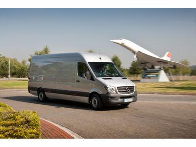 Srebrny van Mercedes-Benz Sprinter na drodze, w tle statyczny model samolotu Concorde.