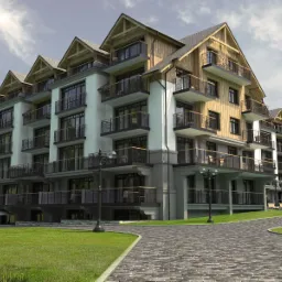Nowoczesny budynek apartamentowy z drewnianymi elementami elewacji, balkonami z ozdobnymi balustradami i zagospodarowanym terenem zielonym z brukowanym chodnikiem i drzewami.