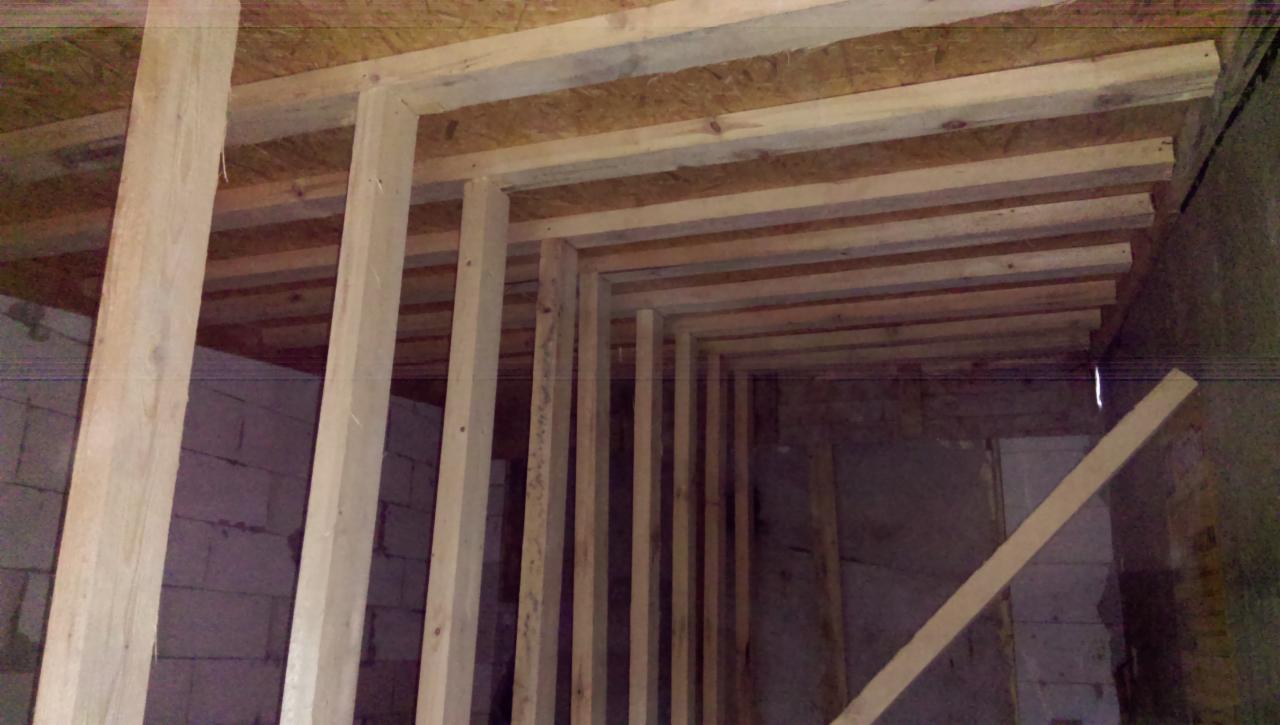 Wnętrze w trakcie budowy domu: widoczne drewniane szkielety ścian i stropu z płyt OSB, surowy stan, ściany z pustaków.