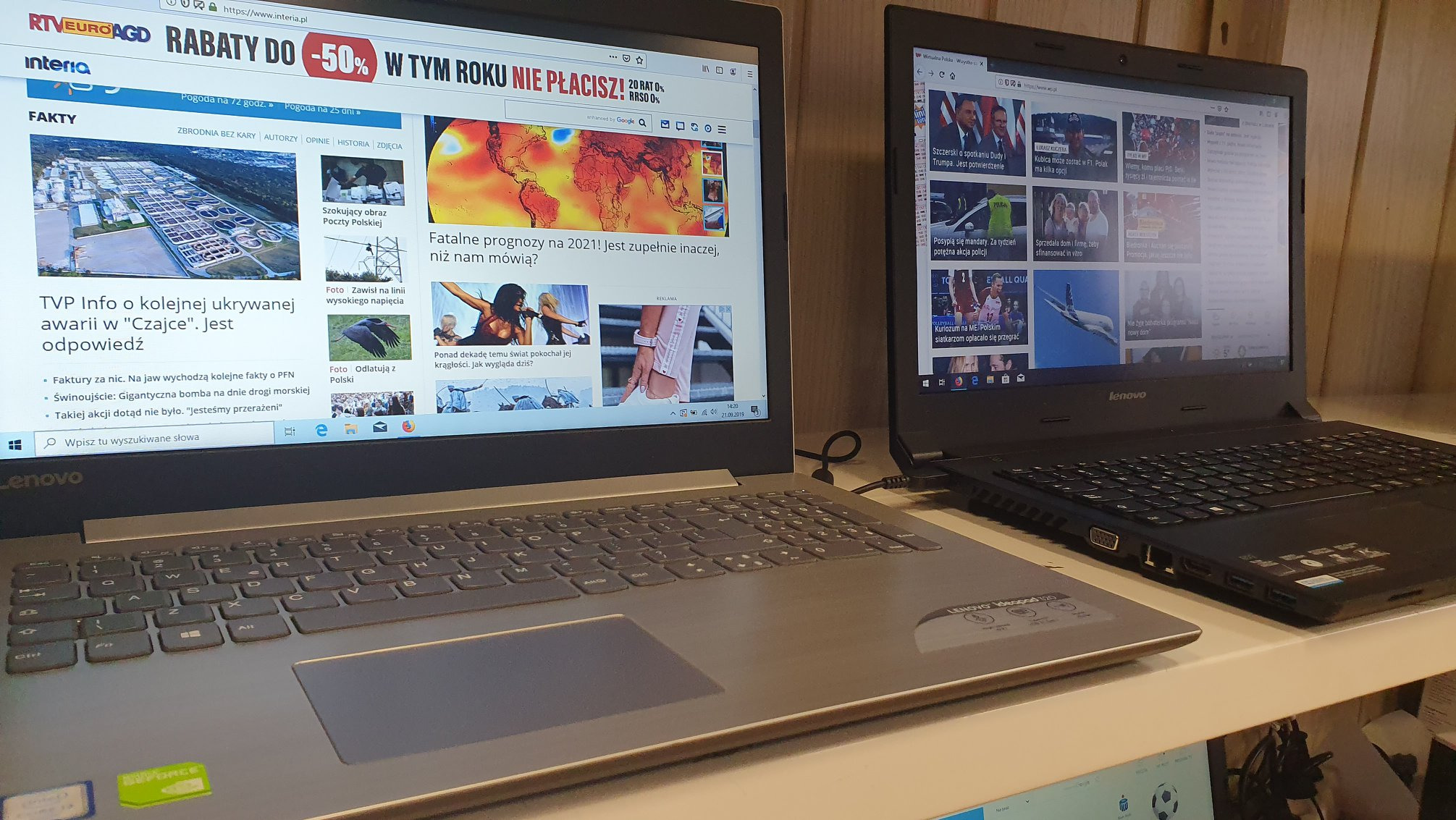 Dwa laptopy Lenovo obok siebie, na ekranie jednego strona główna portalu informacyjnego Interia, na drugim strona Wirtualnej Polski, widoczne klawiatury i touchpady, minimalne oświetlenie.