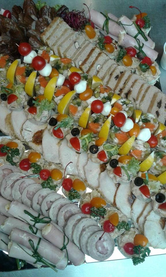 Bogato udekorowany półmisek z wędlinami, pasztetem i galaretkami, ozdobiony pomidorkami koktajlowymi, cytryną i oliwkami.