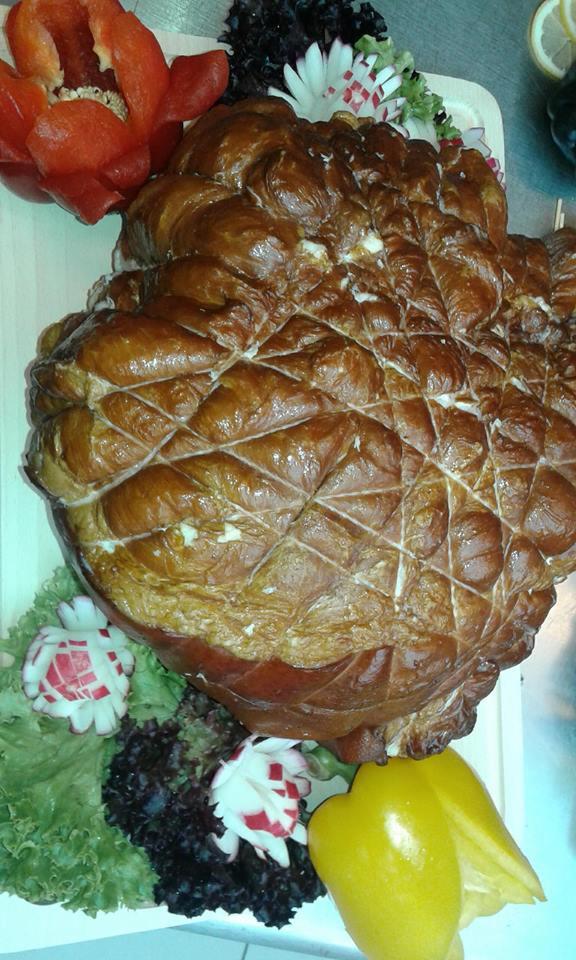 Wędzonka sznurowana, dekoracyjnie ułożona na desce z papryką, rzodkiewką i sałatą karbowaną.