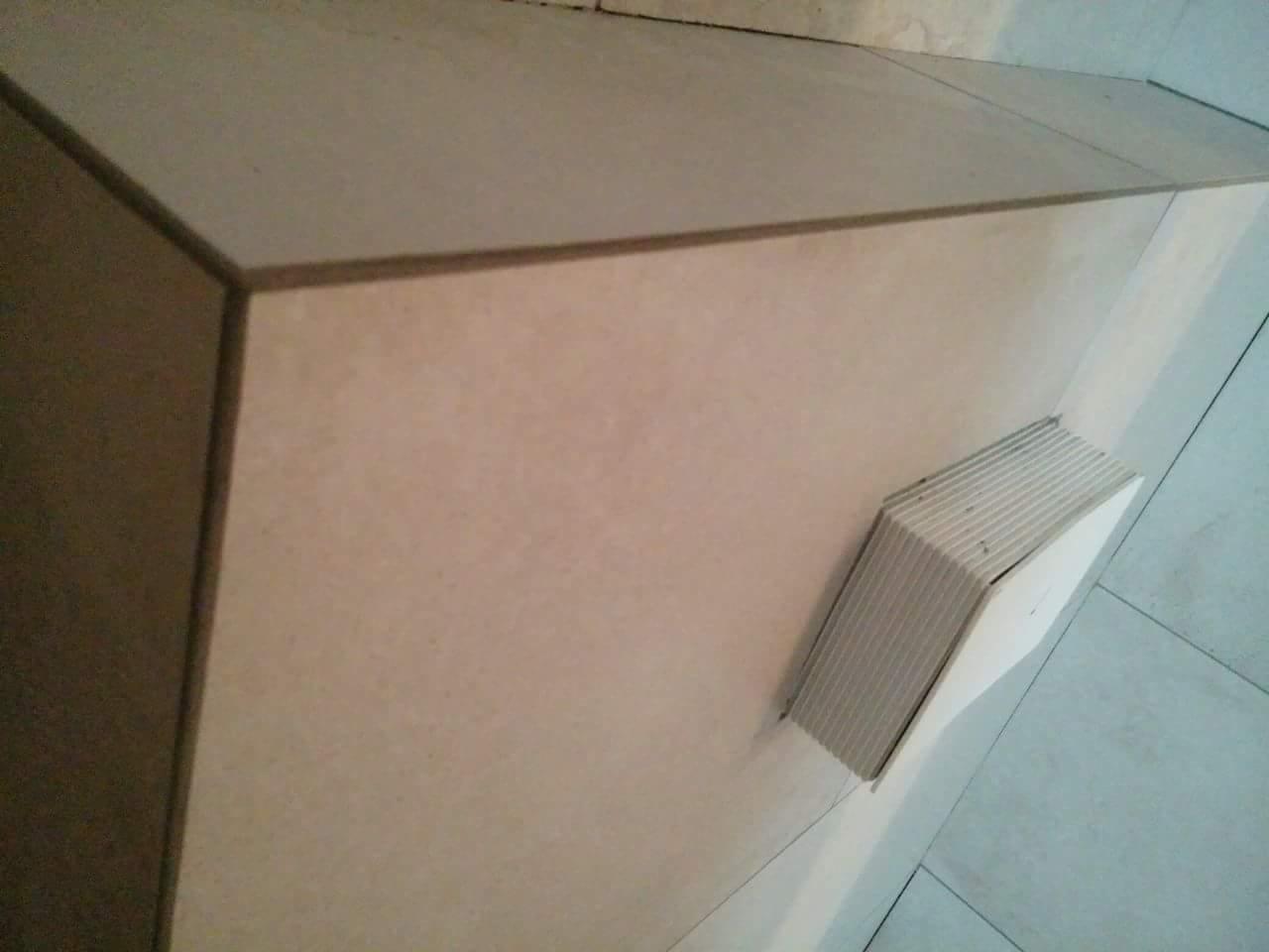 Wykończona obudowa z płytek ceramicznych z widocznym otworem wentylacyjnym, ujęcie z góry pod kątem.