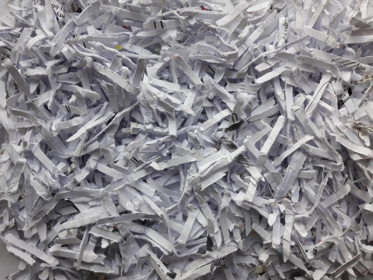 Stos pociętych na paski białych dokumentów z widocznymi fragmentami tekstu i liczb