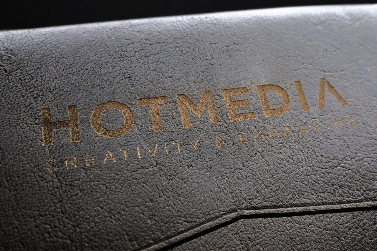 Czarny, teksturowany folder z wytłoczonym złotym napisem HOTMEDIA CREATIVITY & ENGRAVING.
