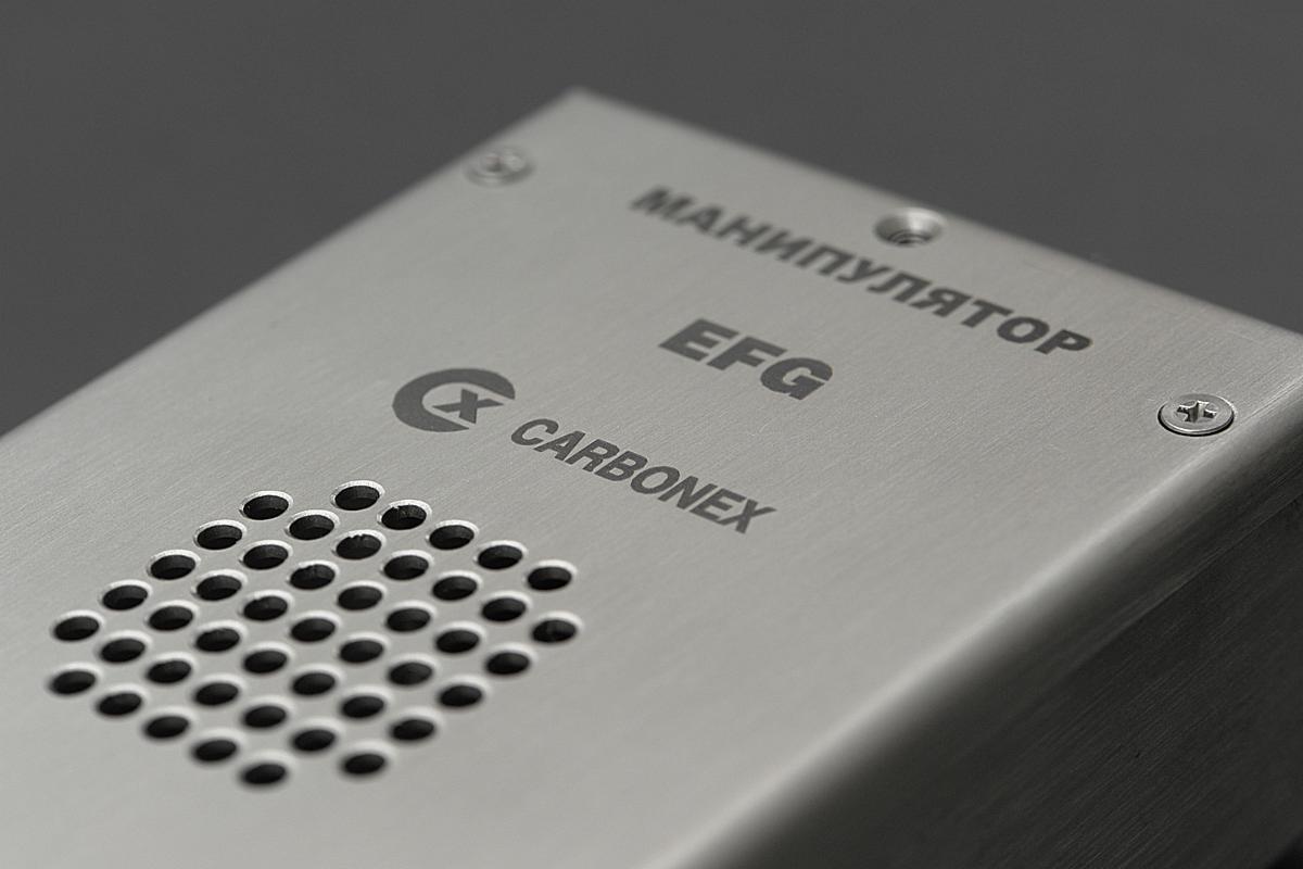 Metalowa obudowa urządzenia z napisem 'МАНИПУЛЯТОР EFG CARBONEX' i perforacją, widoczne śruby mocujące.