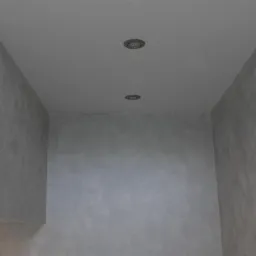 Wnętrze pomieszczenia z szarą, teksturowaną ścianą i dwiema okrągłymi lampami sufitowymi