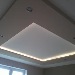 Nowoczesny sufit podwieszany z oświetleniem LED, widoczne reflektory punktowe i geometryczny kształt zabudowy.