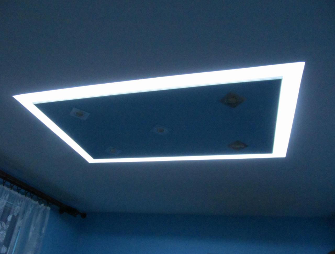 Niebieski sufit z wnęką oświetloną białym światłem LED, widoczne cztery punktowe lampy oświetleniowe.