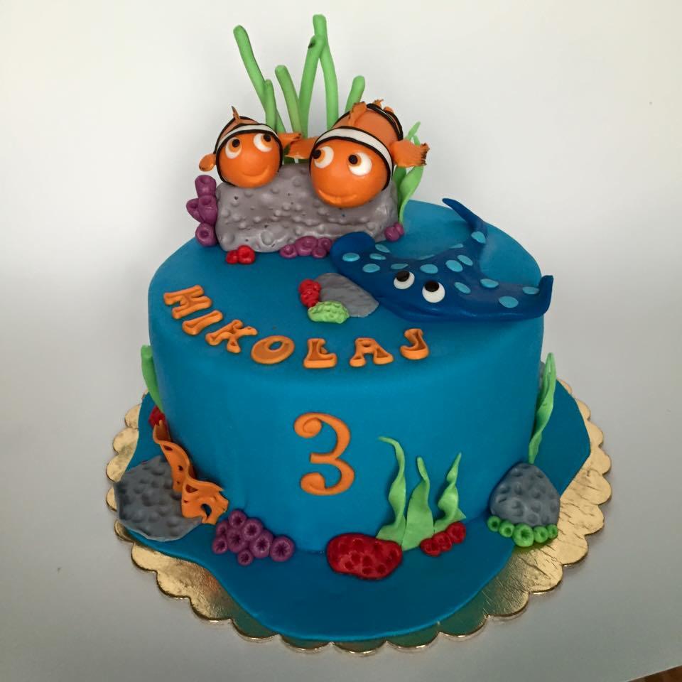 Tort urodzinowy dla trzylatka z motywem podwodnego świata, dekorowany figurkami rybek Nemo i płaszczki Manta, imieniem Mikołaj napisanym pomarańczowymi literami.