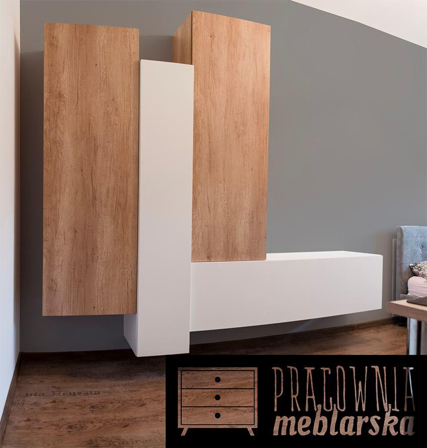 Nowoczesna szafka RTV z drewnopodobnymi frontami i białymi elementami, zawieszona na ścianie, z logo pracowni meblarskiej w rogu.