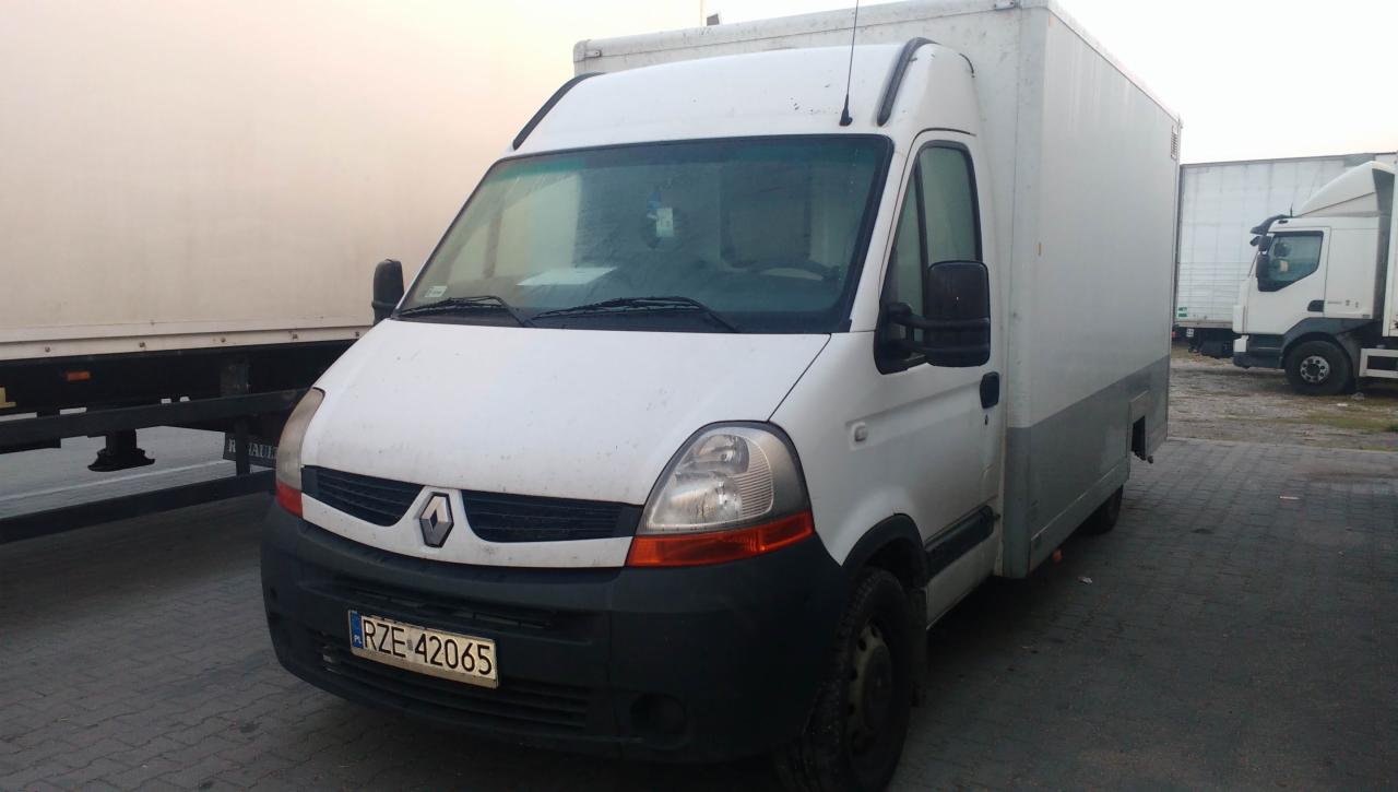 Biały samochód dostawczy Renault Master z zabudową kontenerową, zaparkowany na placu z innymi pojazdami dostawczymi w tle.