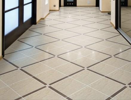 Beżowa podłoga z płytek ułożonych w romby z ciemnobrązowymi akcentami, widok z perspektywy wejścia do pomieszczenia z przeszklonymi drzwiami.